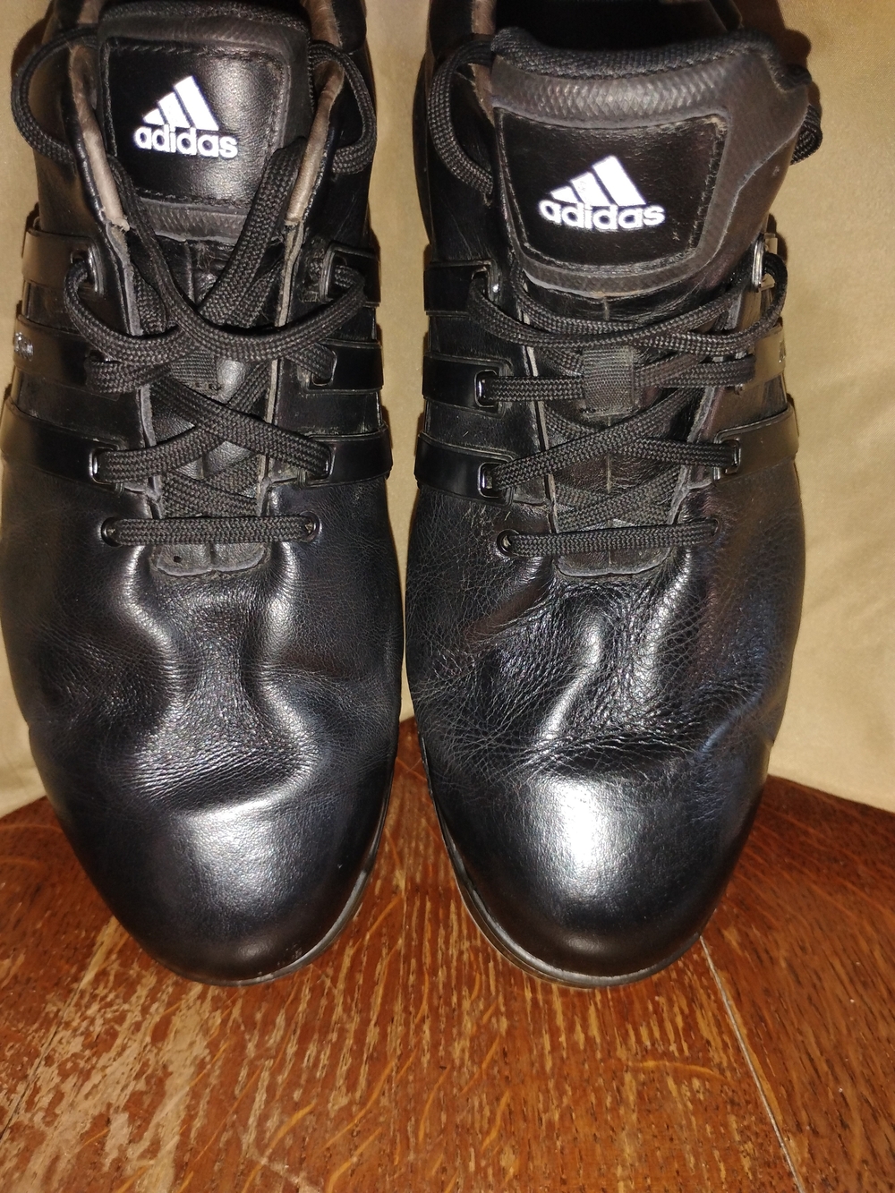 Adidas Tour 360 golf shoes with lace-up closures and distinct black stripes.